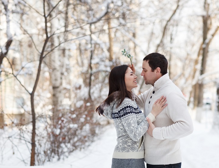 Happy young couple under mistletoe having fun in the winter park